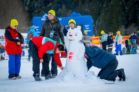 Sportler*innen und Betreuer*innen bauen einen Schneemann bei Special Olympics Nationalen Winterspielen